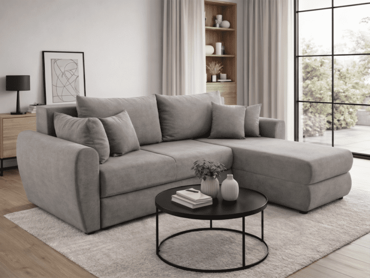 Modern living room with a gray sectional sofa, round black coffee table, and light-filled window view.