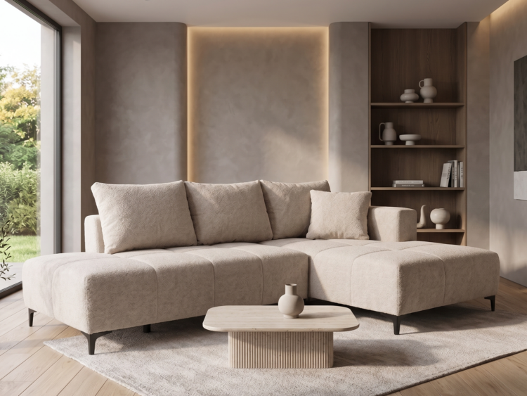 Neutral beige sectional sofa in a modern living room with a wooden bookshelf, round coffee table, and large window showing greenery outside.