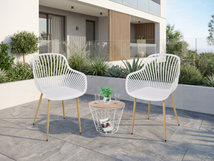 Two white contemporary patio chairs flanking a small round table with a plant on a tiled terrace in front of a modern building.