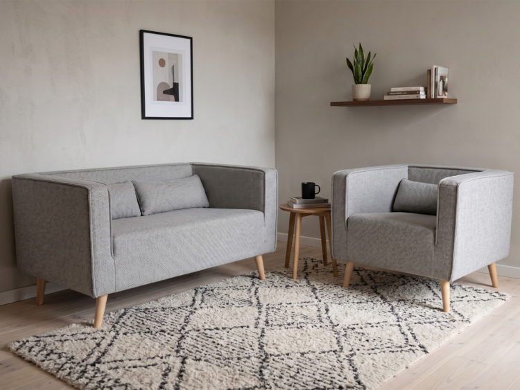 Two light-gray, mid-century chairs face each other with a small wooden side table between them in a cozy living room scene.