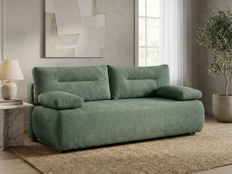 Green corduroy sofa with matching cylindrical arm cushions in a sunlit living room, next to a marble side table and lamp on a jute rug.