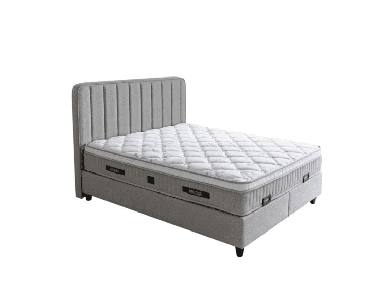 Grey upholstered bed with a tall, vertically tufted headboard and a thick quilted mattress; built-in storage drawers along the base.