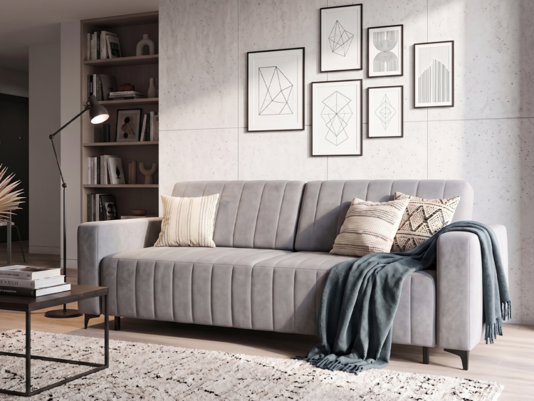 Gray tufted sofa in a contemporary living room with geometric art on a concrete wall and a cozy throw blanket on the armrest.