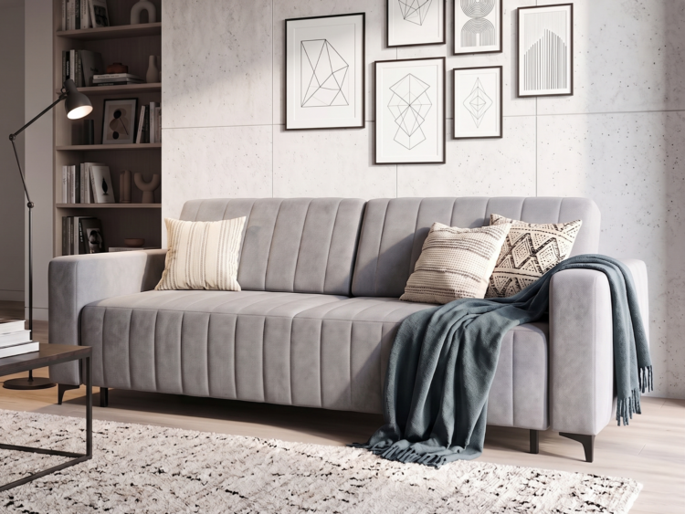 Gray upholstered sofa with two patterned throw pillows and a teal blanket in a modern living room set-up with a gallery wall and bookshelf nearby](https://)