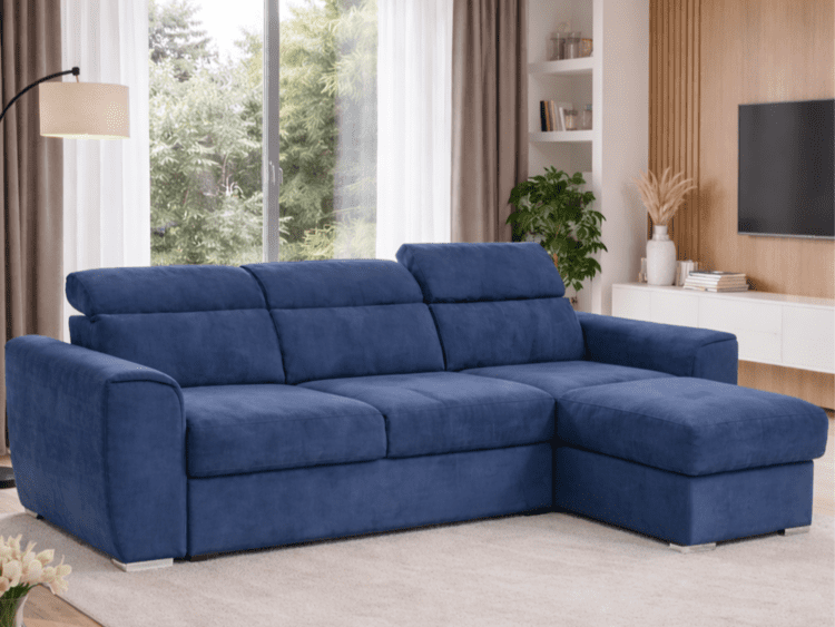 Blue L-shaped sofa in a bright living room with a large window and white shelving unit nearby. ashing brown curtains and a plant add style to the space.