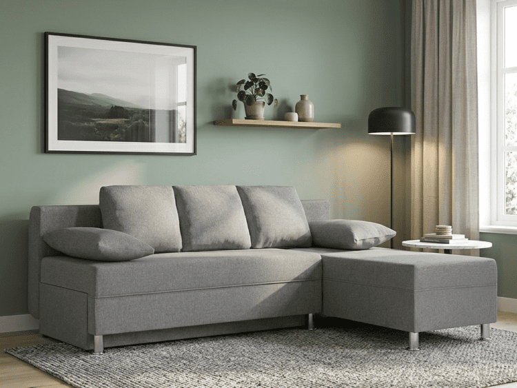 Gray L-shaped sofa with chaise on a patterned rug in a living room with a green wall and window.