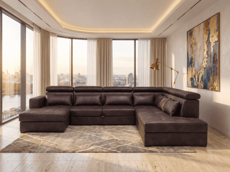 Dark brown L-shaped sectional sofa in a sunlit modern living room with floor-to-ceiling windows overlooking a city skyline.