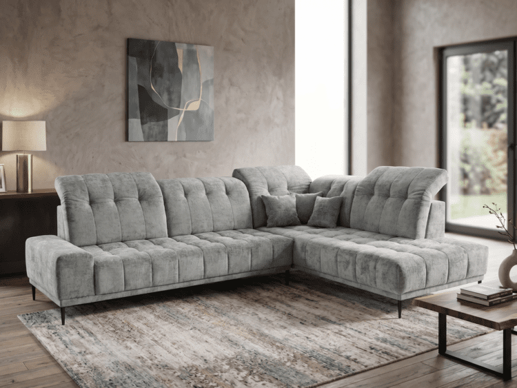 L-shaped gray tufted sectional sofa in a modern living room with abstract wall art and a textured beige wall.