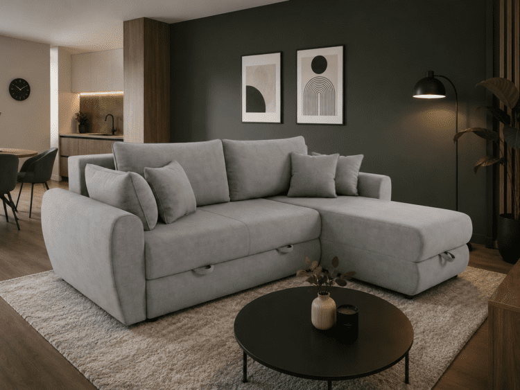Gray L-shaped sofa with multiple cushions in a modern living room, dark accent wall, and a round black coffee table nearby on a light rug.