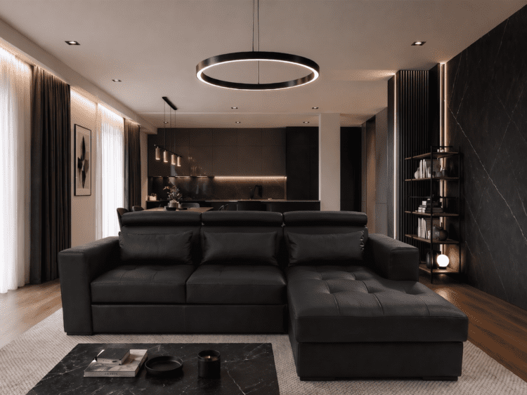 Open-plan living room with a black leather sectional, marble coffee table, and circular ring chandelier in front of a dark kitchen area.