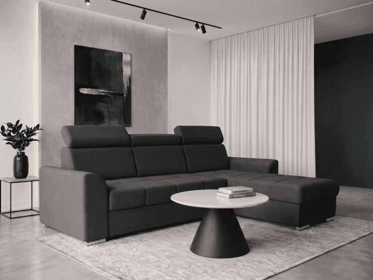 Modern living room with a dark gray sectional sofa, round marble coffee table, and a gray rug; abstract green artwork on the wall and a green vase with a plant on a side table to the left.