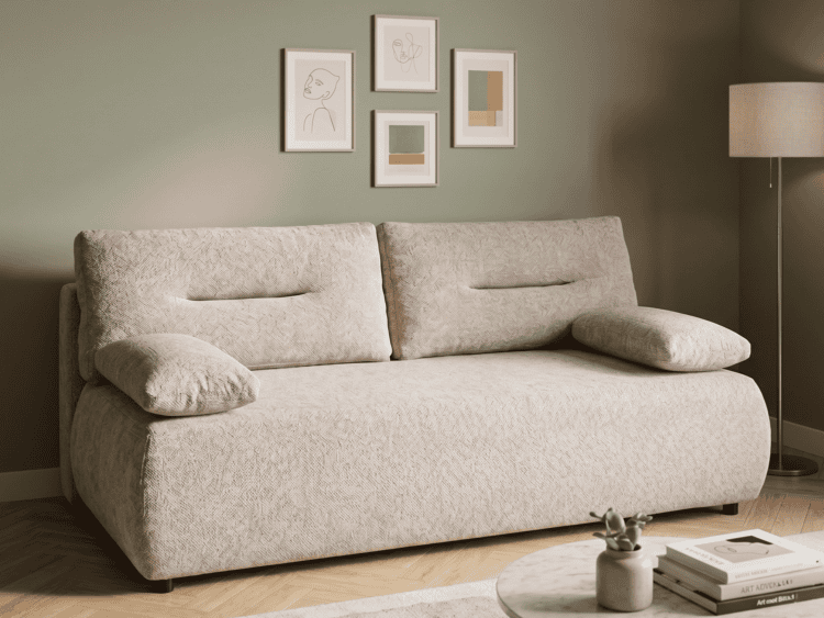 Beige textured sofa in a living room with four framed abstract line-art prints on an olive wall and a floor lamp to the right.