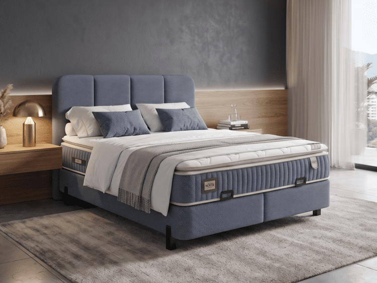 Blue upholstered king-size bed with white bedding and gray throw in a modern bedroom, next to a wooden nightstand with a lamp and books by a large window